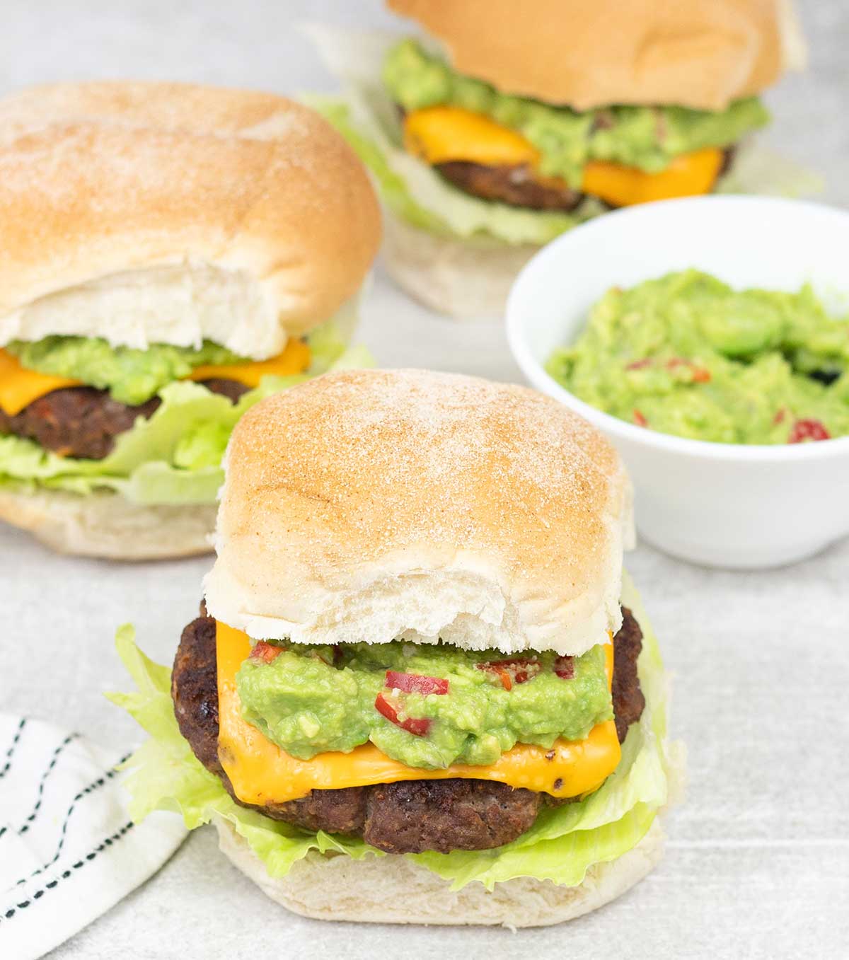 3 Mexican burgers and a small bowl of guacamole.