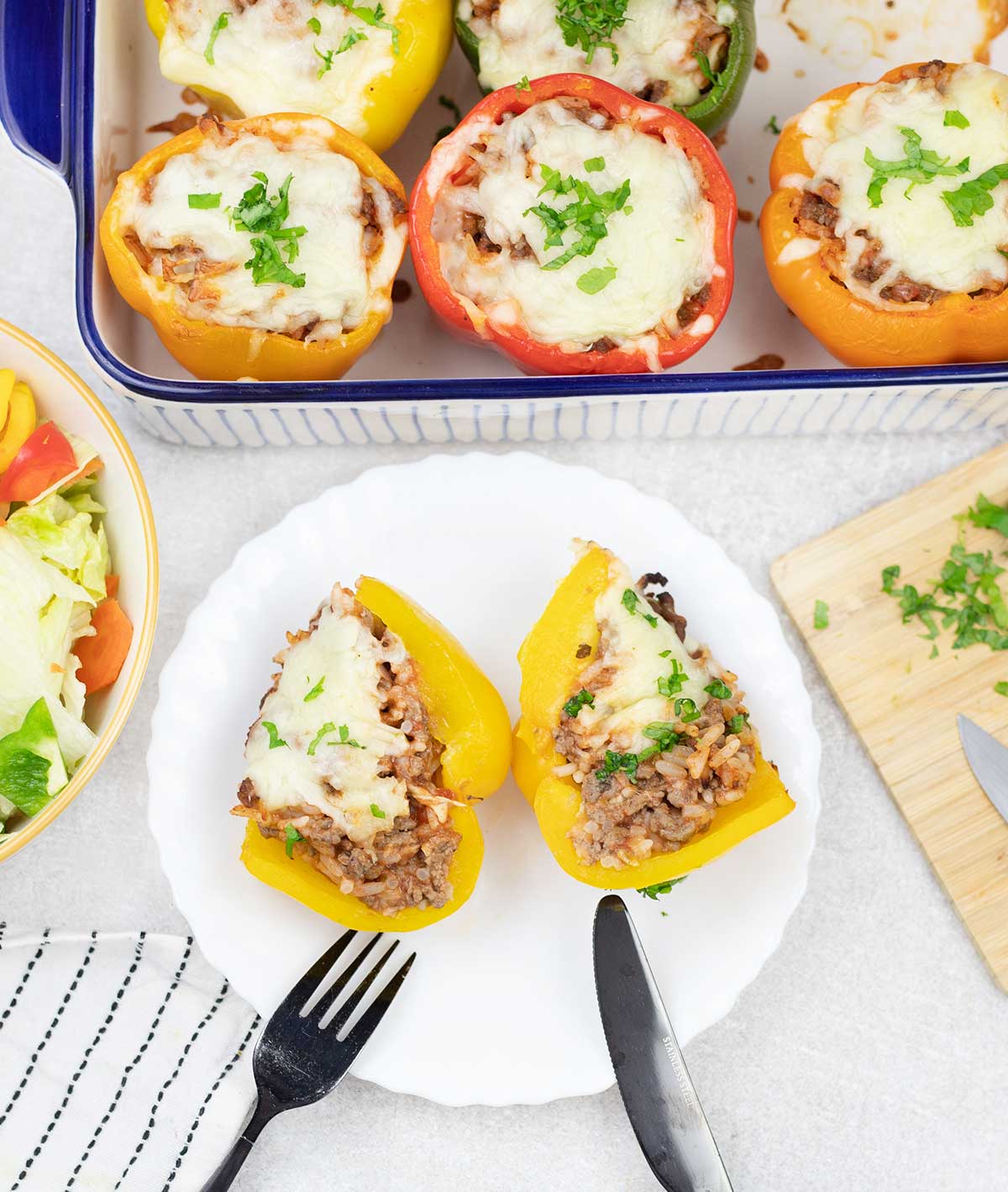 One baked stuffed bell pepper cut in a plate and some stuffed bell pepper are in the background.