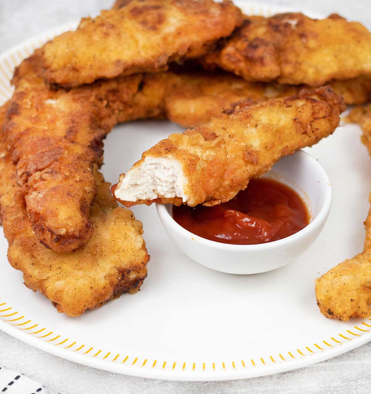 Fried chicken fingers and a bowl of ketchup.
