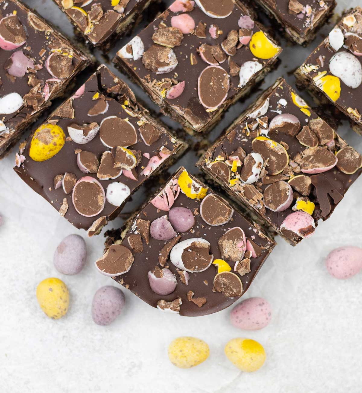 Slices of Easter chocolate tiffin studded with mini eggs on a table.