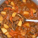 Beef stew with tomato sauce and veggies in a pot.