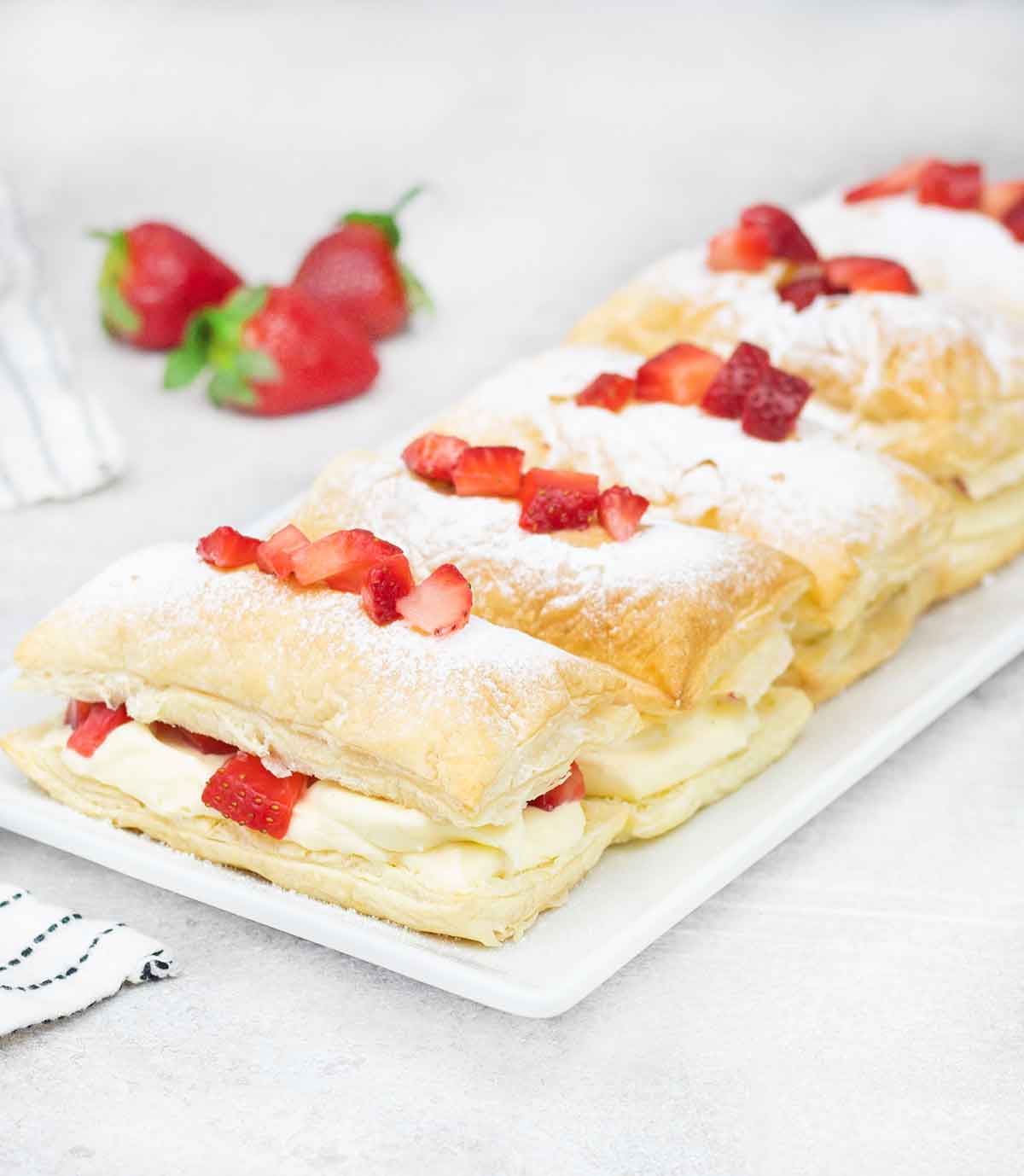 Strawberry Mille Feuille in a serving plate and strawberries in the background.