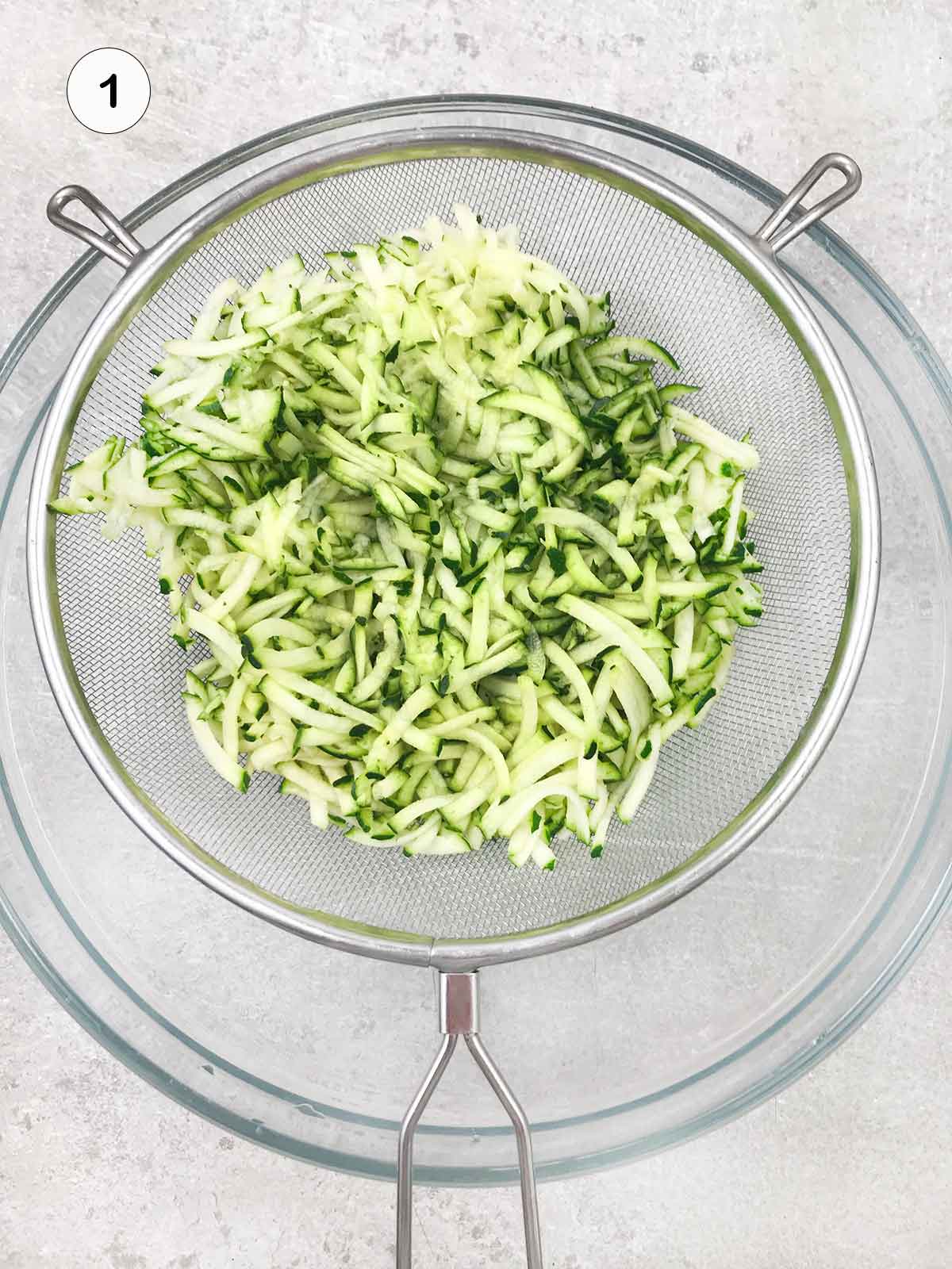 Shredded zucchini in a colander.