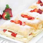 strawberry mille feuille topped with fresh strawberries and powdered sugar.