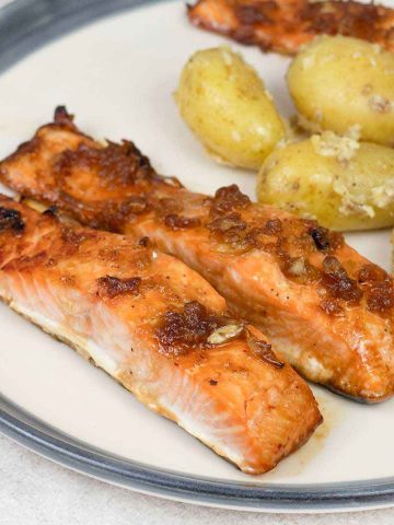 baked honey glazed salmon and baby potatoes in a plate.