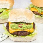 Mexican burgers topped with cheese and guacamole.
