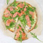 smoked salmon pizza topped with arugula.