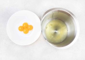 In 2 different mixing bowls, separate the egg whites from the yolks.