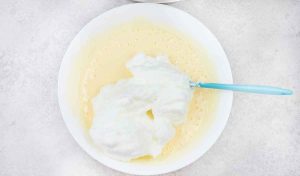 folding the egg whites into the yolk mixture gradually and slowly using a spatula.