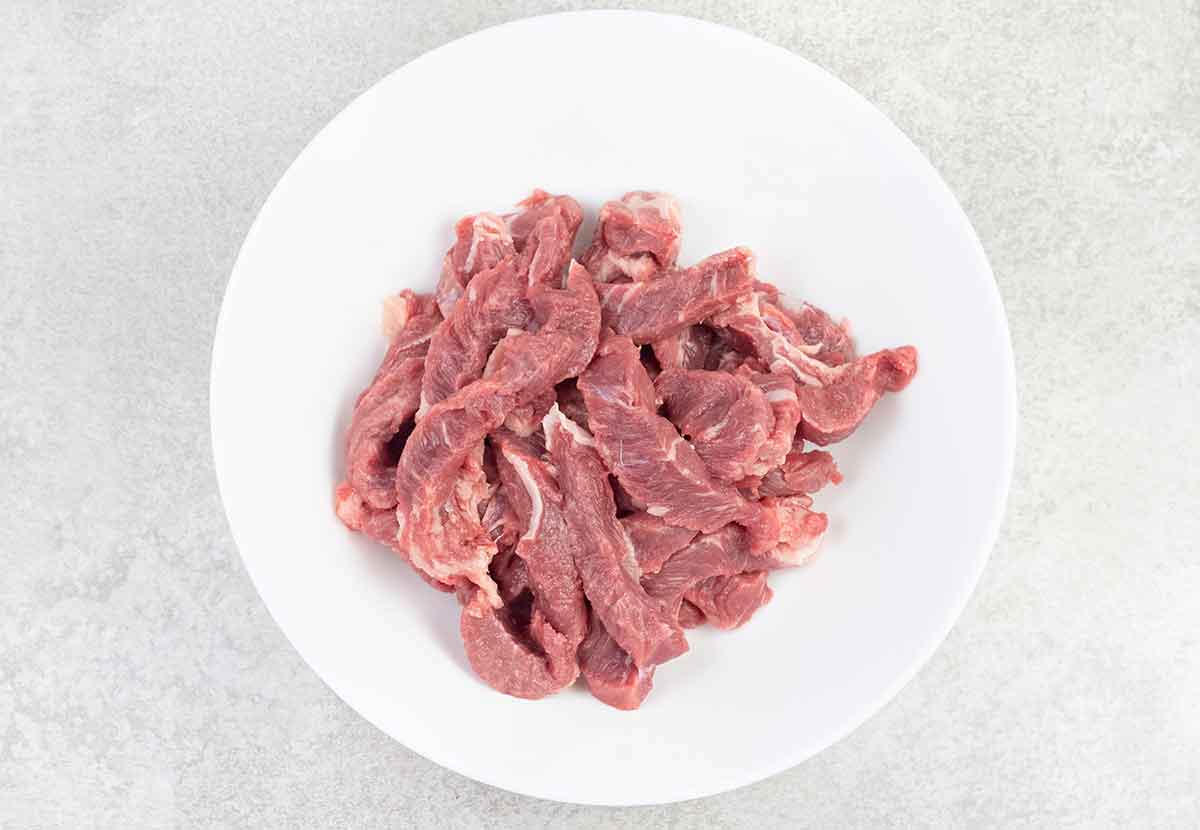 Cut the beef into thin strips and add them to a large bowl.