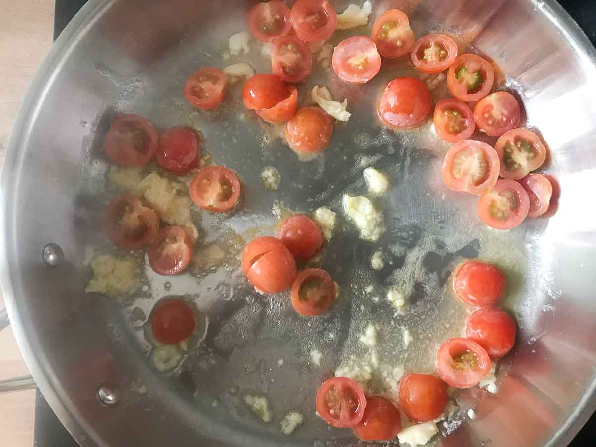 In the same pan, add butter to melt, add the garlic and tomatoes and cook.