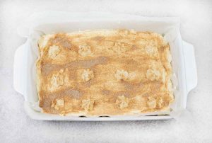 Spread the cheesecake filling on top of the cooled churro base and sprinkle the cinnamon sugar on top.