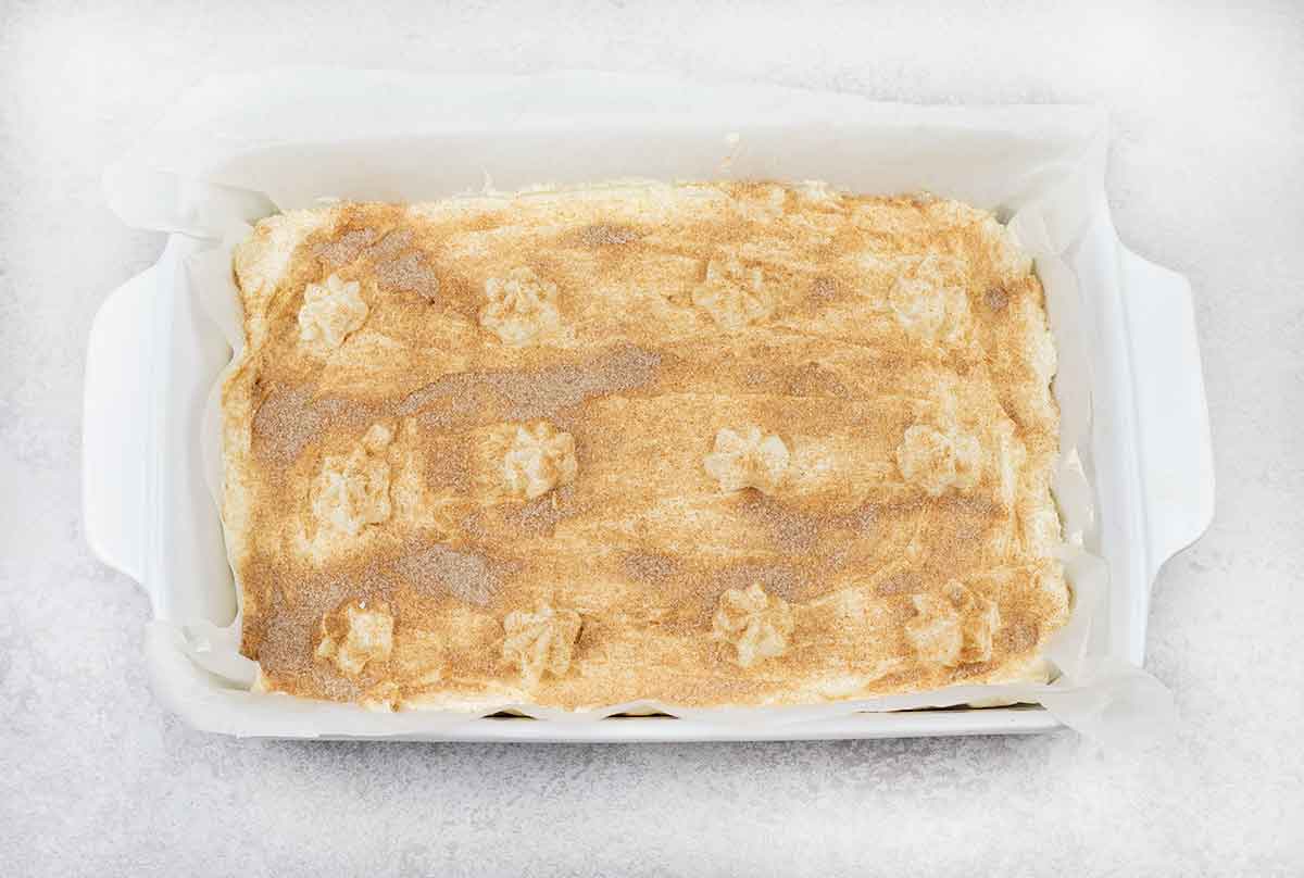 Spread the cheesecake filling on top of the cooled churro base and sprinkle the cinnamon sugar on top.