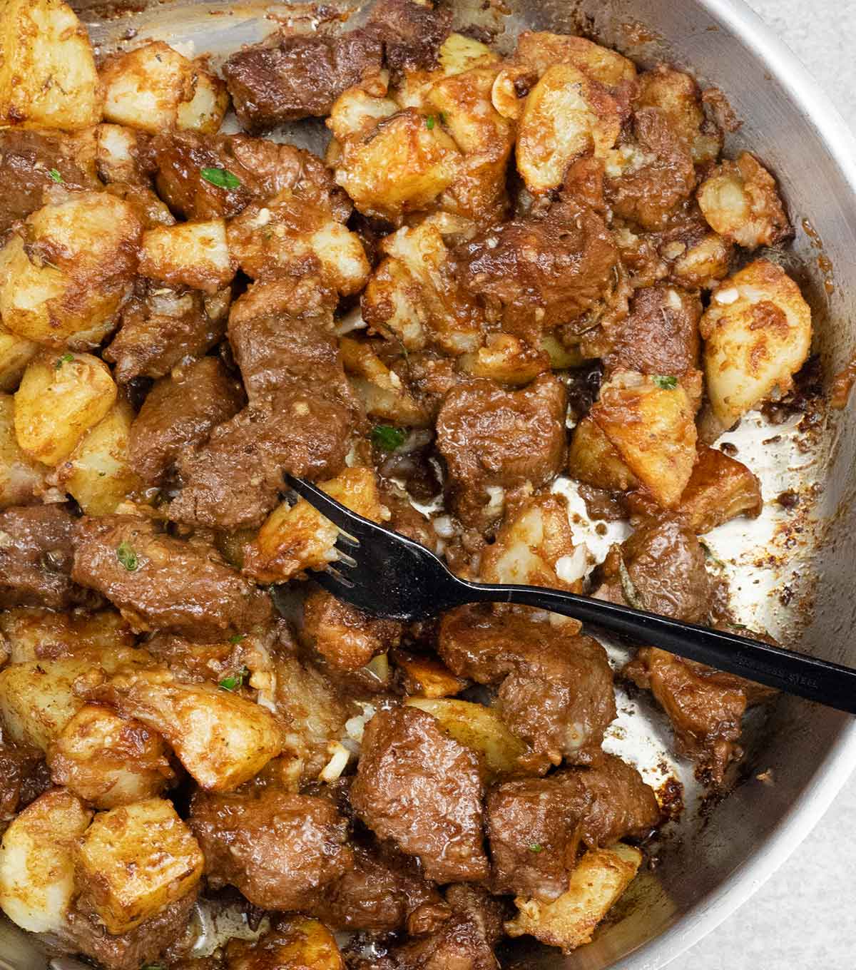 garlic steak and potatoes in a frying pan.