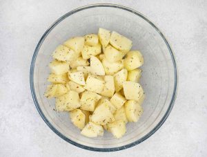 in a mixing bowl, mix the potatoes with Italian seasoning, 1 teaspoon salt, 1 teaspoon garlic powder and 1 tablespoon olive oil.
