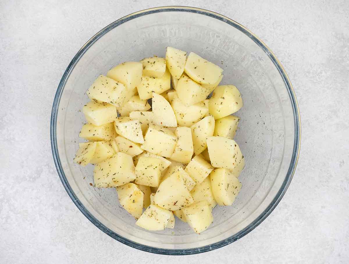 in a mixing bowl, mix the potatoes with Italian seasoning, 1 teaspoon salt, 1 teaspoon garlic powder and 1 tablespoon olive oil.