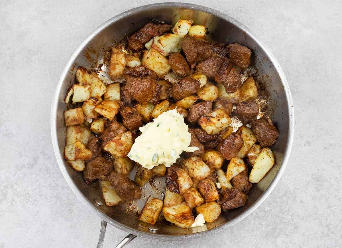 Add the potatoes to the skillet with the steak, then stir in the garlic herb butter.