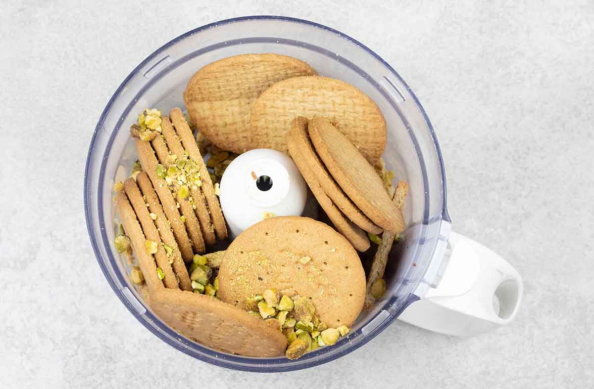 To make the crust, add the biscuits and pistachios to the food processor.