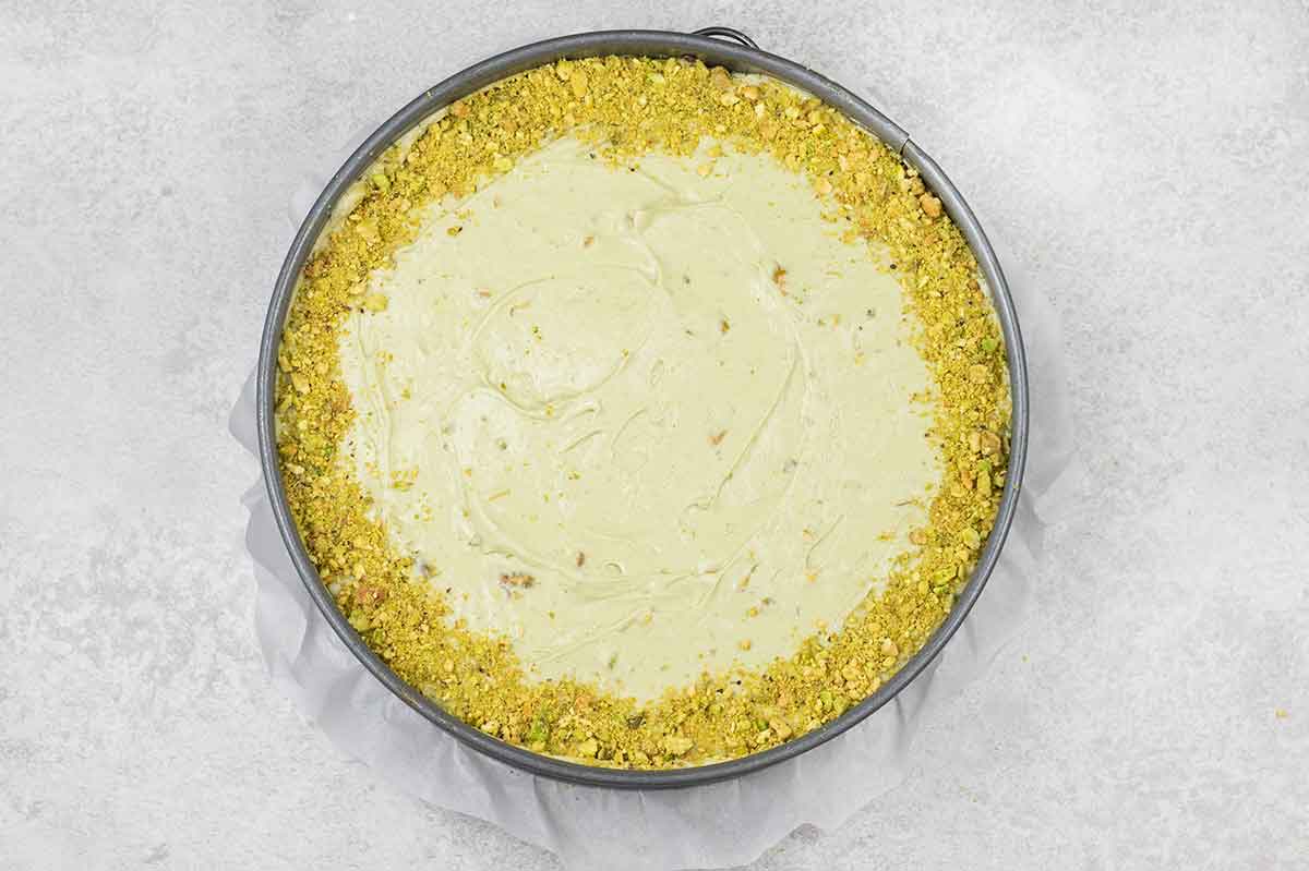 Sprinkle the crushed pistachios all around the edges of the cheesecake.