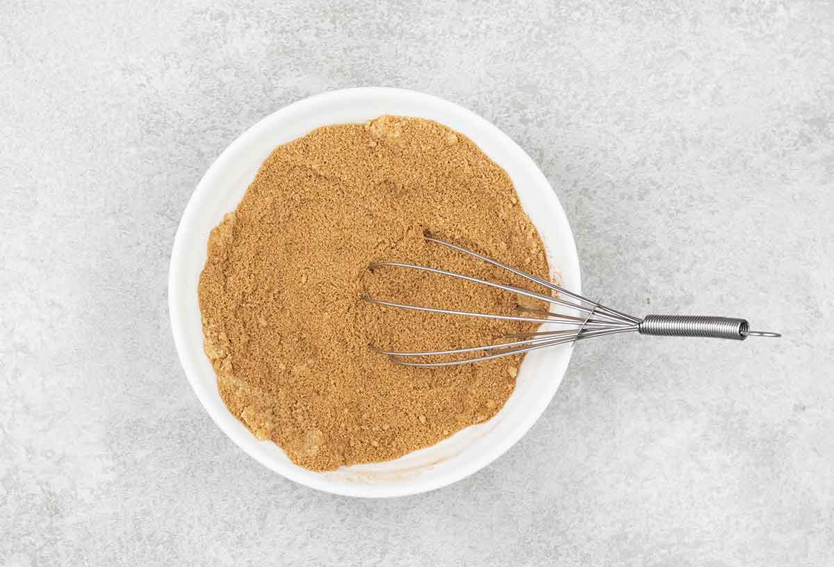 a small bowl filled with a mixture of brown sugar and ground cinnamon and a whisk.