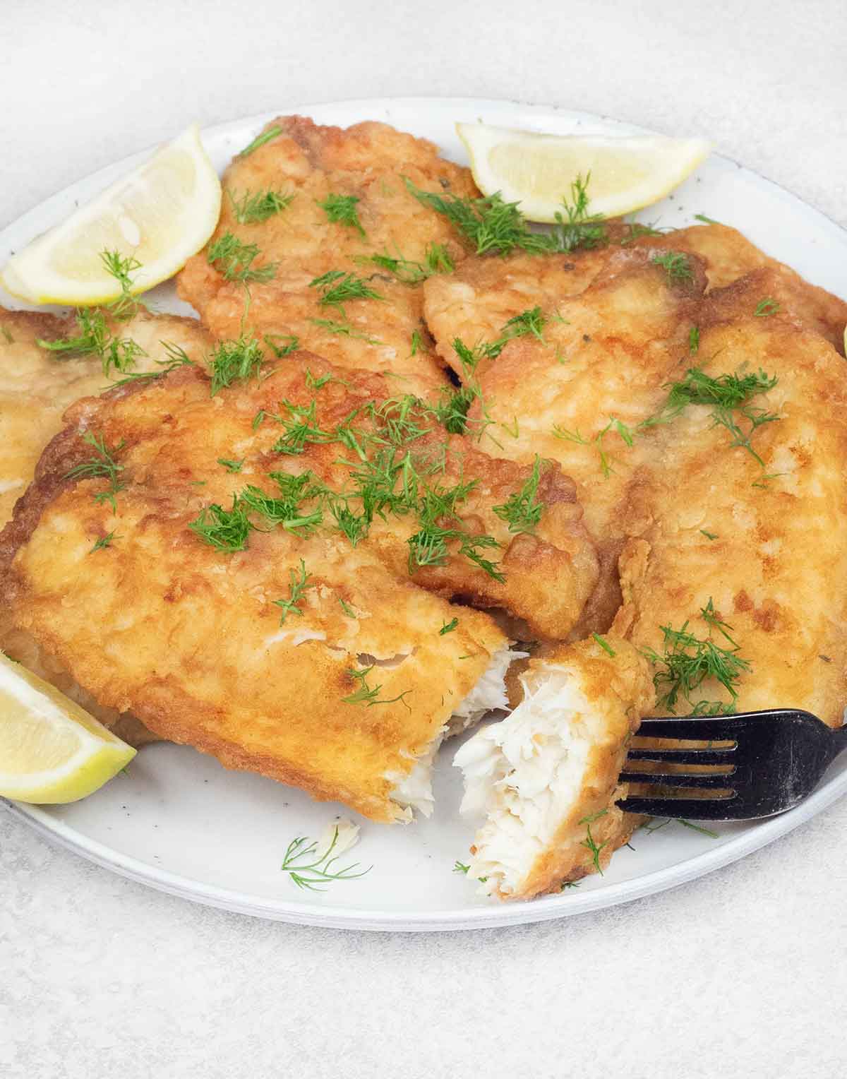 A thick forkful of crispy fried tilapia fillet.