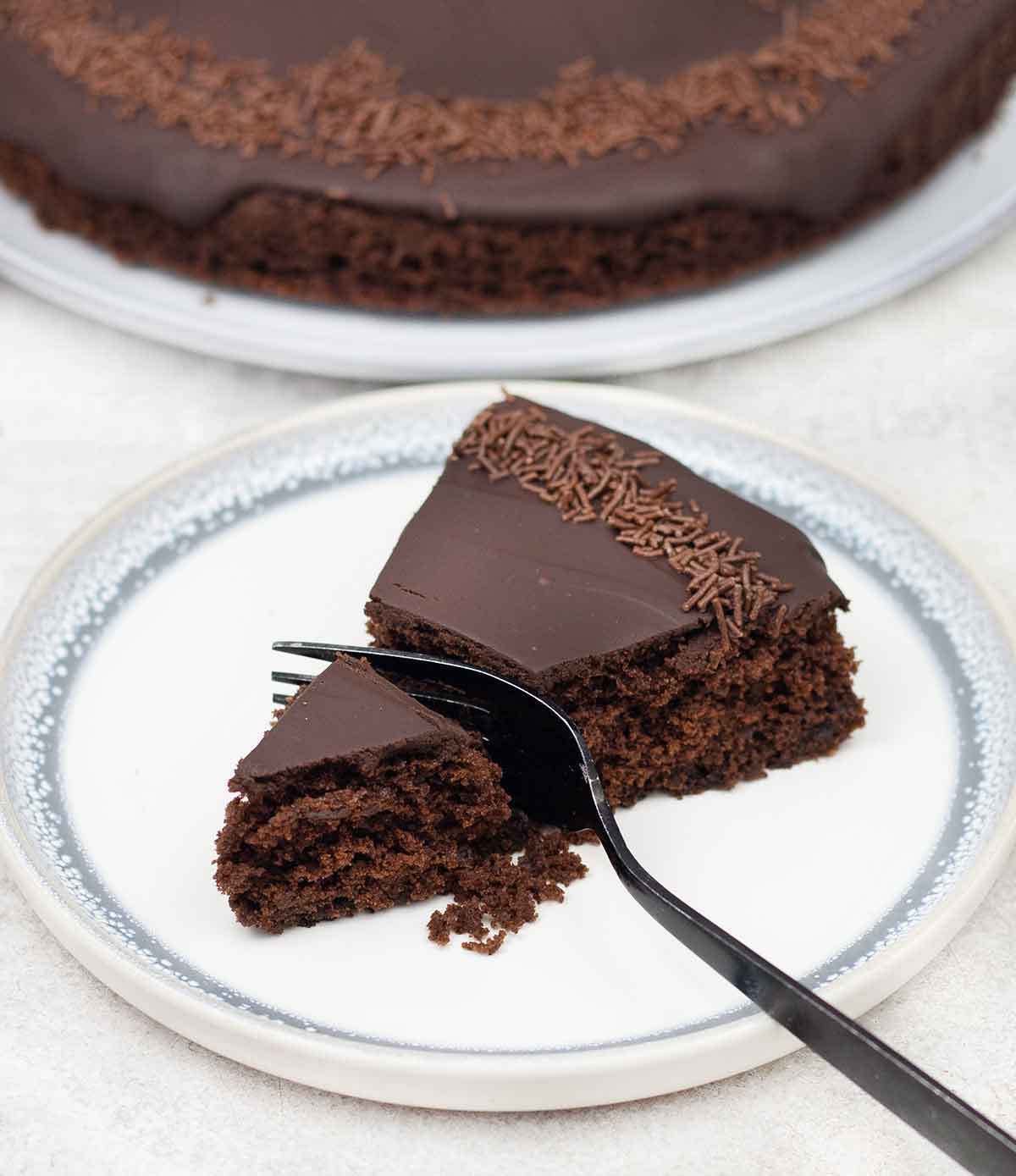 Close-up slice of moist single layer chocolate cake with ganache and chocolate sprinkles